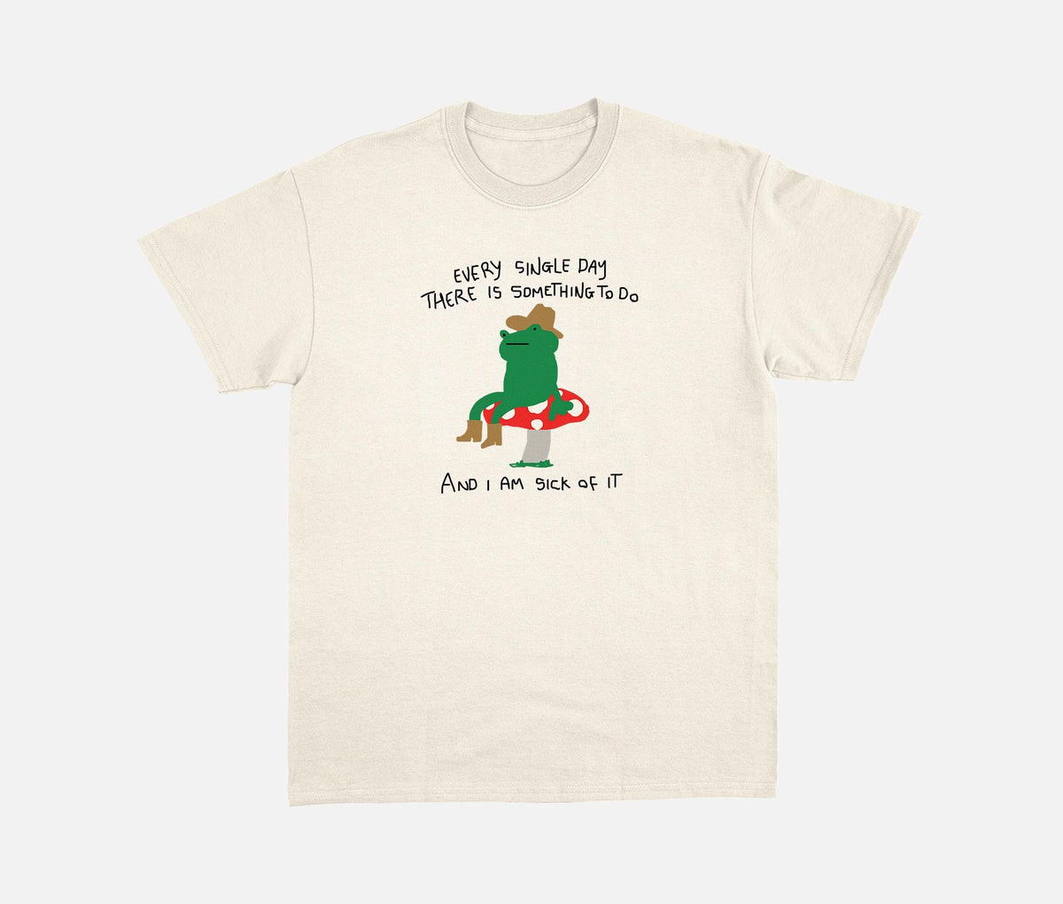Natural T-shirt with a cowboy frog on a mushroom and a humorous daily-task quote.