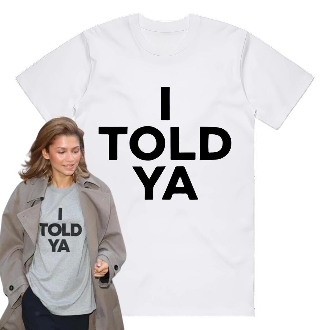 May include: White t-shirt with black text that reads "I TOLD YA".