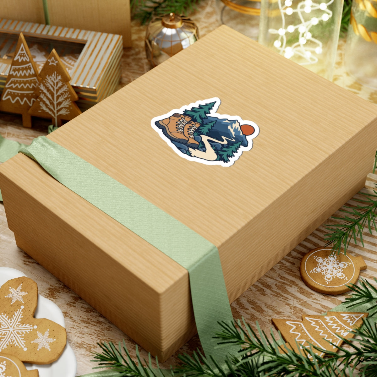 Hiking boots and fir trees sticker shown on a kraft gift box with a green ribbon