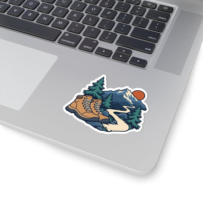 Hiking boots, mountain trail and fir trees sticker shown on a silver laptop beside the keyboard