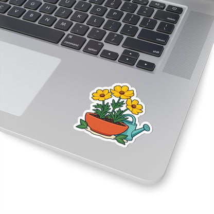Yellow flower pot and teal watering can sticker shown on a silver laptop beside the keyboard