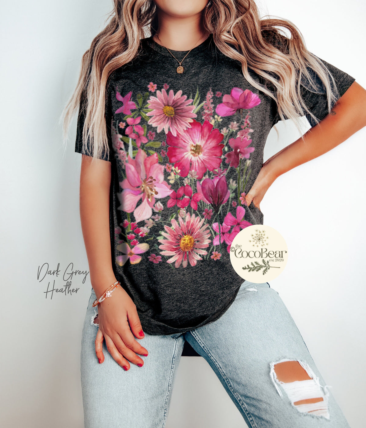 May include: Dark grey heather t-shirt featuring a vibrant floral design in shades of pink and magenta. The design includes various flowers and foliage. The text "The CocoBear" is visible on the right side of the shirt.