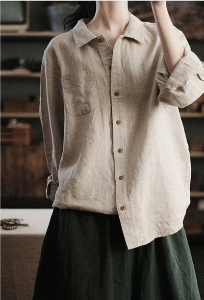 May include: A beige linen button-down shirt with a single chest pocket and long sleeves. The shirt is unbuttoned and has a relaxed fit.