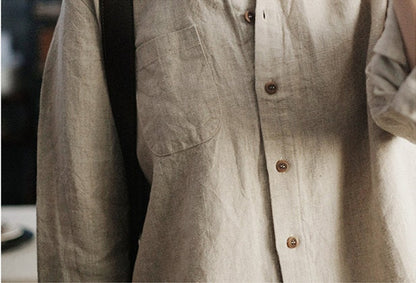 May include: A light brown linen shirt with a button-up front and a single pocket on the left chest.