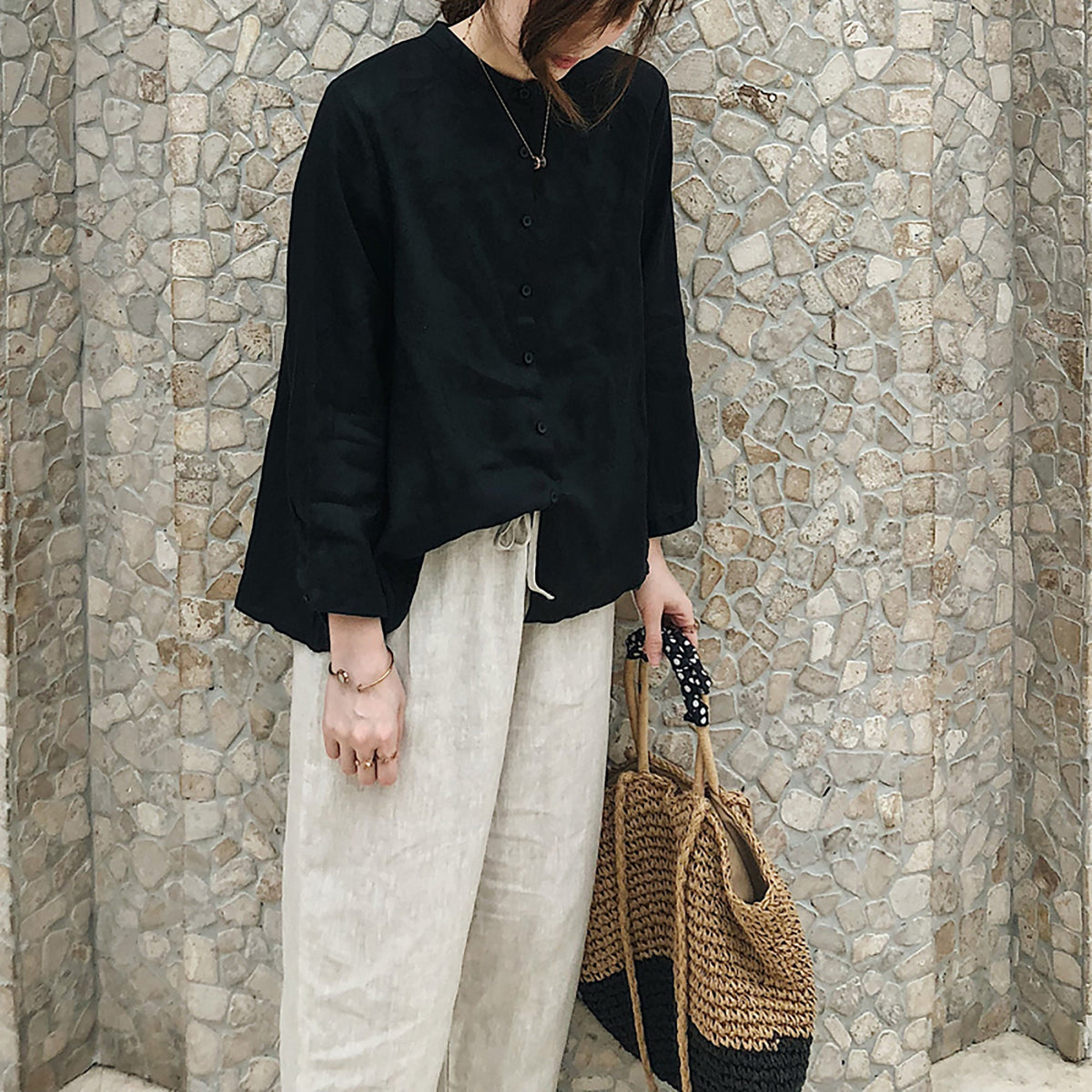May include: A black long-sleeved button-down shirt with a relaxed fit and a straw tote bag with black polka dot trim.