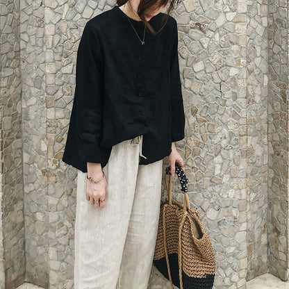 May include: A black long-sleeved button-down shirt with a relaxed fit and a straw tote bag with black polka dot trim.