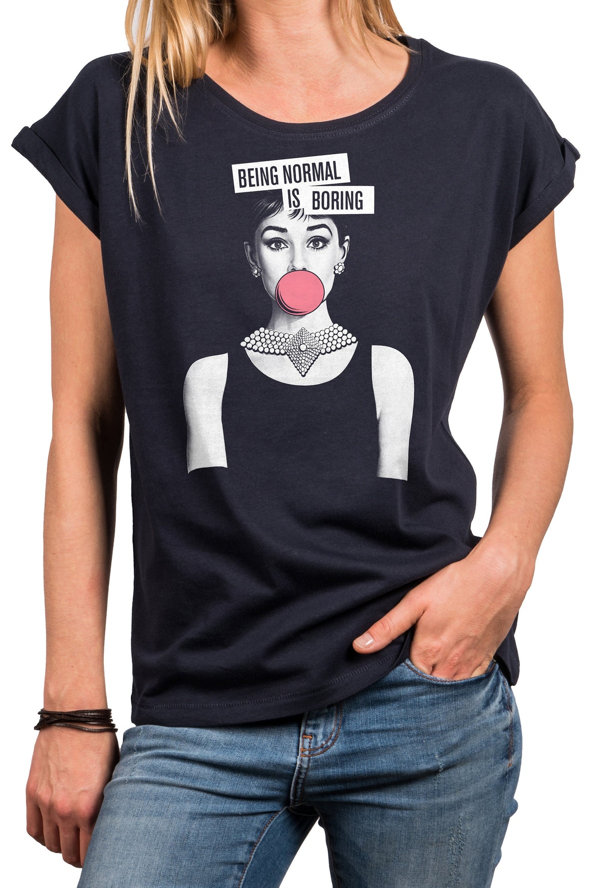May include: Dark navy blue t-shirt featuring a graphic of a woman with a pink bubblegum bubble and a pearl necklace. The text "BEING NORMAL IS BORING" is above the graphic. The shirt has rolled sleeves.