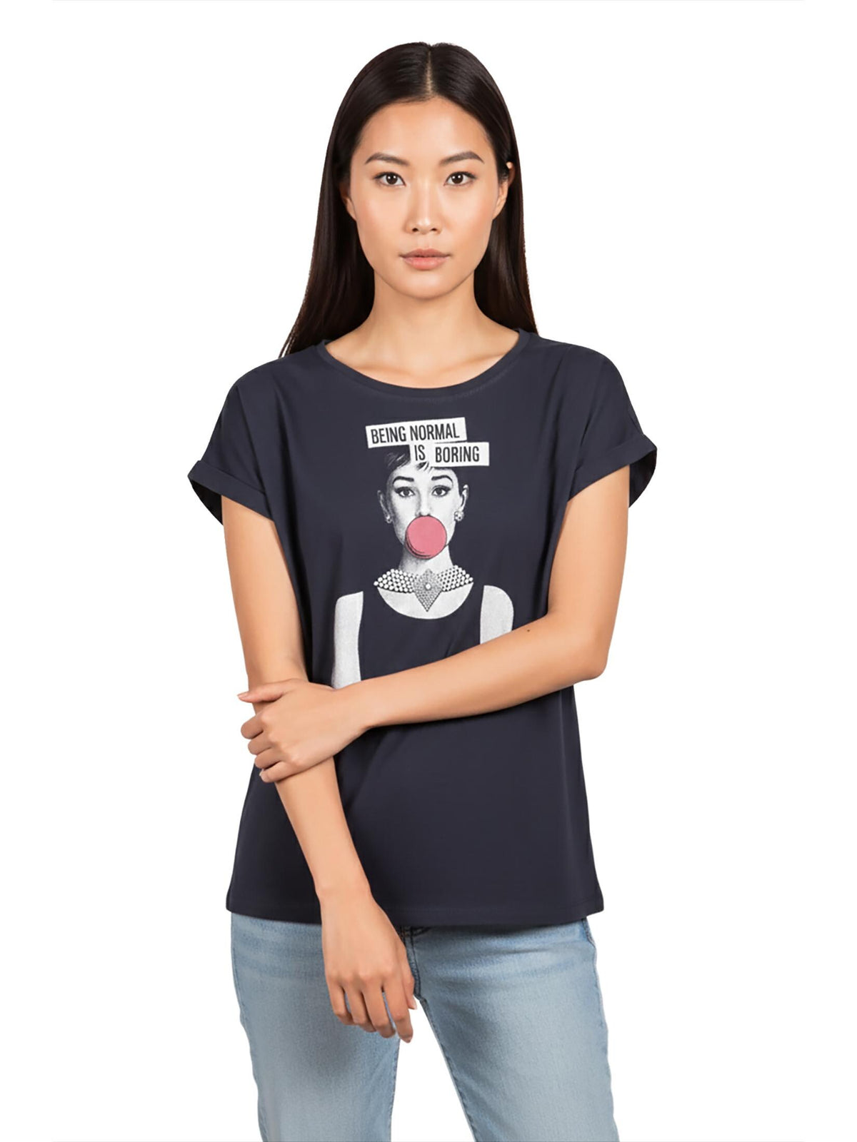 May include: Navy blue t-shirt featuring a black and white graphic of a woman blowing a bubblegum bubble. The text "BEING NORMAL IS BORING" is above the graphic. The shirt has rolled sleeves and is paired with light blue jeans.