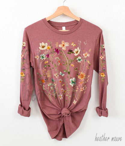 May include: A long-sleeved t-shirt with a floral print in shades of pink, yellow, and green. The shirt is heather mauve.