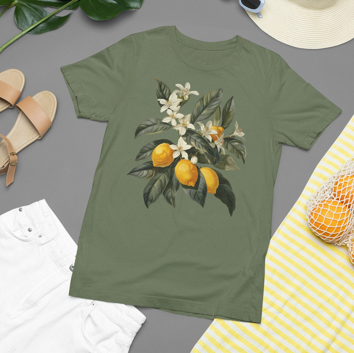 May include: A green t-shirt with a vintage illustration of a lemon tree branch with white blossoms and yellow lemons.