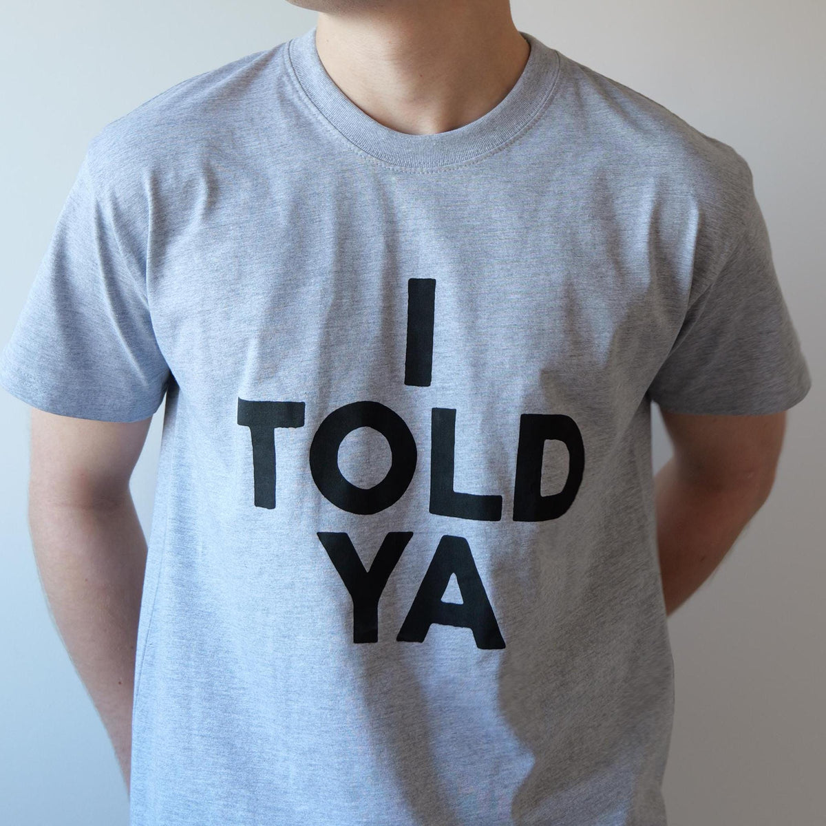 May include: A gray t-shirt with the text "I TOLD YA" printed in black.