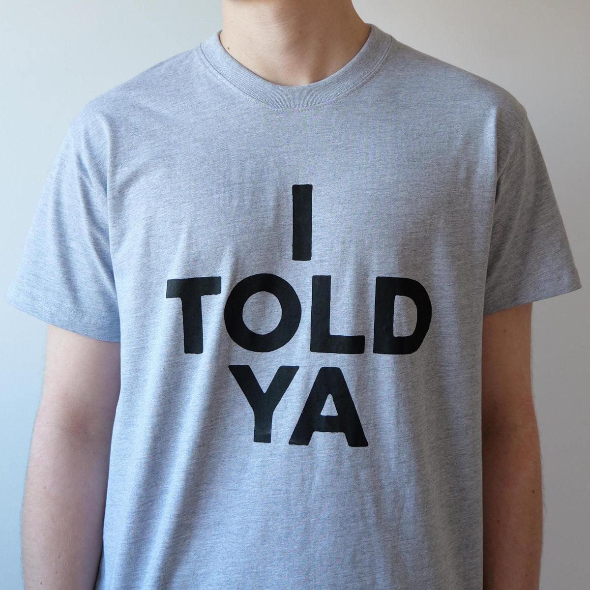 May include: A gray t-shirt with black text that reads "I TOLD YA".