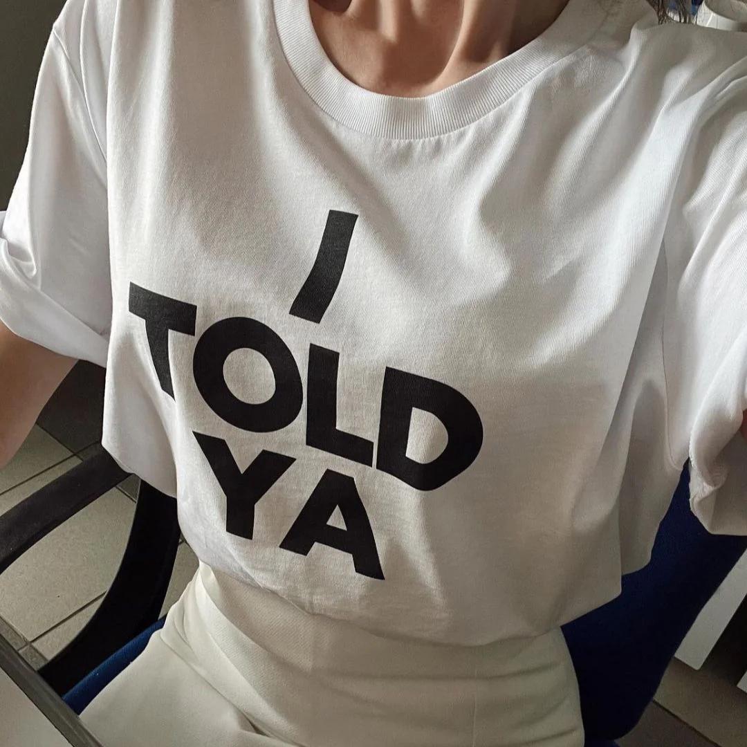 May include: White t-shirt with black text that reads "I told ya".