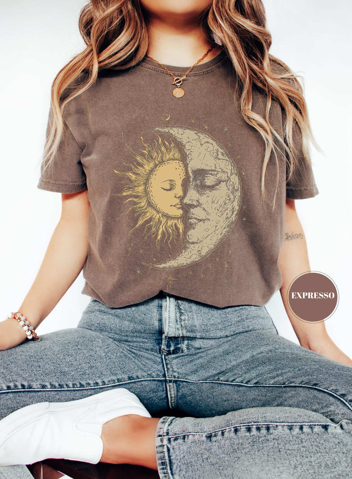 May include: Brown t-shirt featuring a celestial design with a sun and moon graphic. The sun is yellow, and the moon is beige. The shirt is worn with blue jeans. The word "EXPRESSO" is printed on a brown circle.