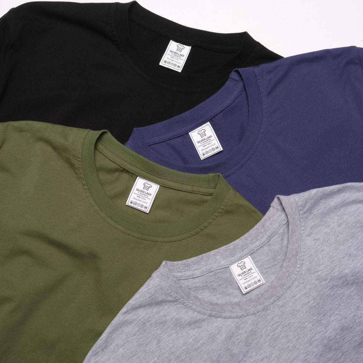 May include: A collection of crew neck t-shirts in various colors: black, navy blue, olive green, and gray. Each shirt has a small white tag with text. The shirts are made of a soft material.