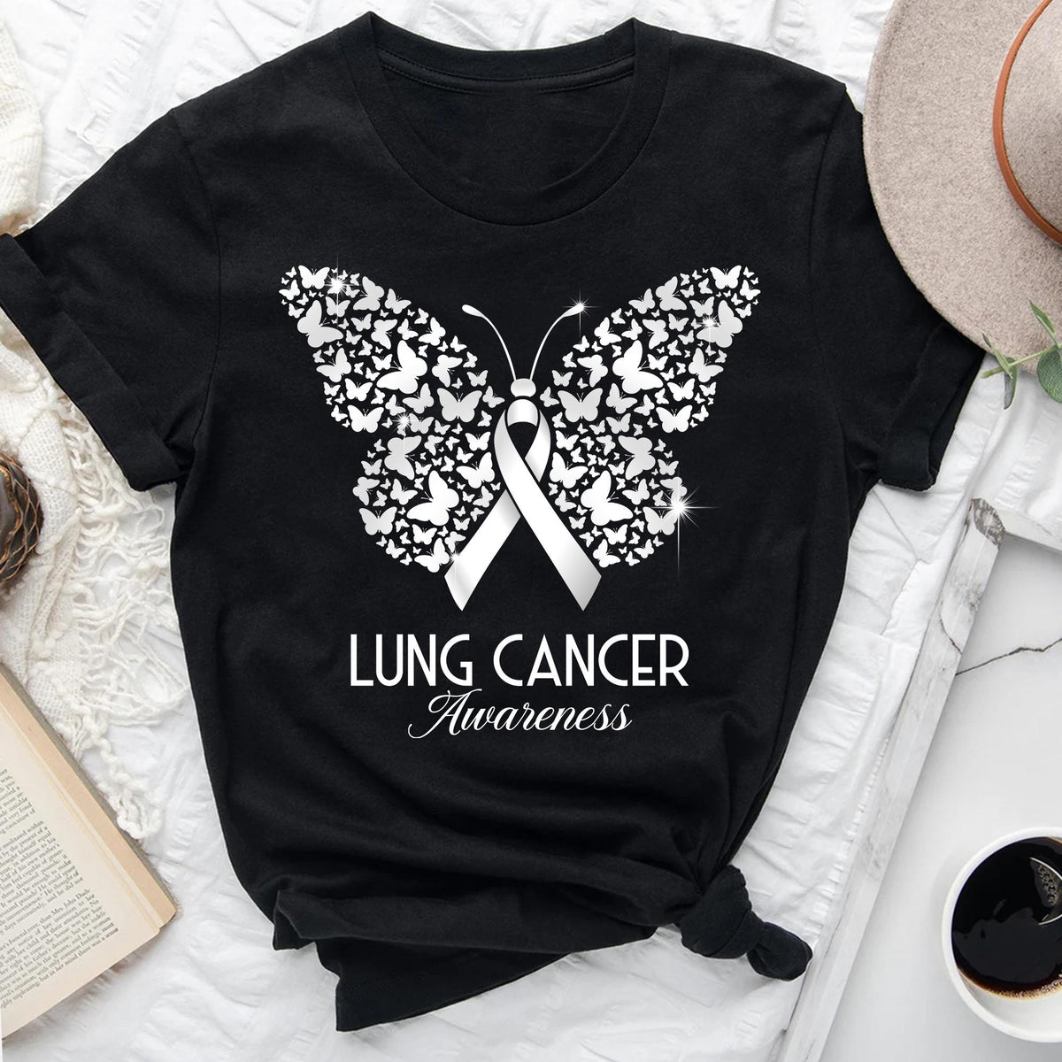 May include: Black t-shirt featuring a white butterfly design composed of smaller butterflies. A white ribbon is centered within the butterfly, with the words "LUNG CANCER Awareness" below in a script font. The shirt is displayed on a white surface.