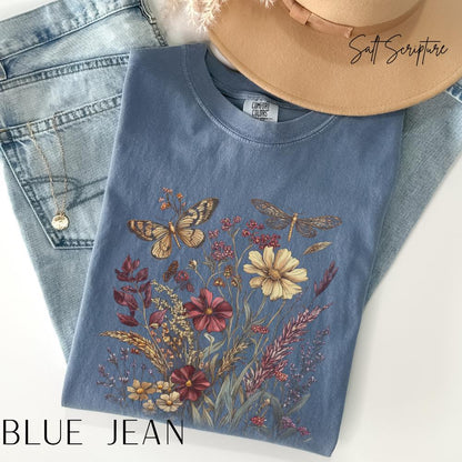 May include: A blue jean colored t-shirt with a floral and insect design. The design includes butterflies, a dragonfly, and various flowers in shades of yellow, red, and purple. The text "BLUE JEAN" is at the bottom of the image.