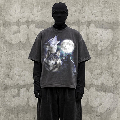 May include: Dark gray t-shirt featuring a graphic of three wolves howling at a full moon. The shirt has a vintage, distressed look. The model is wearing a black turtleneck and black pants.