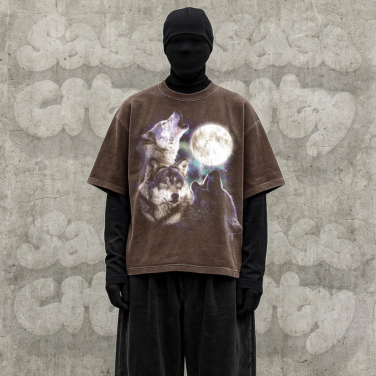 May include: Brown t-shirt featuring a wolf pack howling at a full moon. The graphic tee has a vintage, distressed look. The shirt is worn over a black long-sleeve shirt and black pants.
