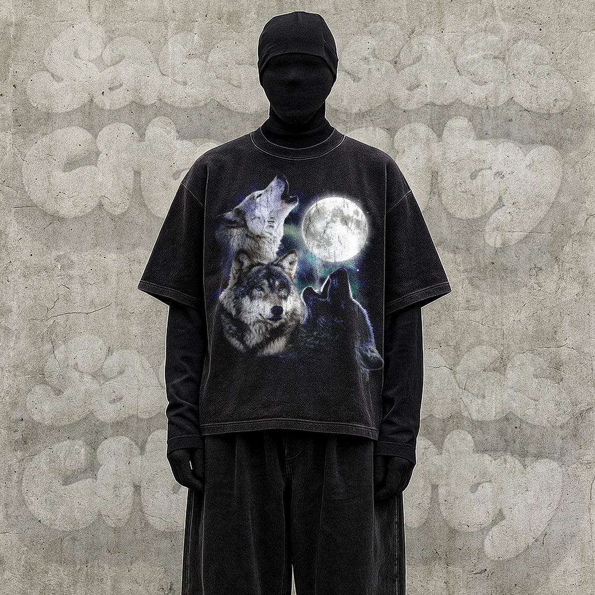 May include: Black t-shirt featuring a graphic of three wolves howling at a full moon. The shirt is worn over a black long-sleeve shirt and black pants. The background is a gray concrete wall.