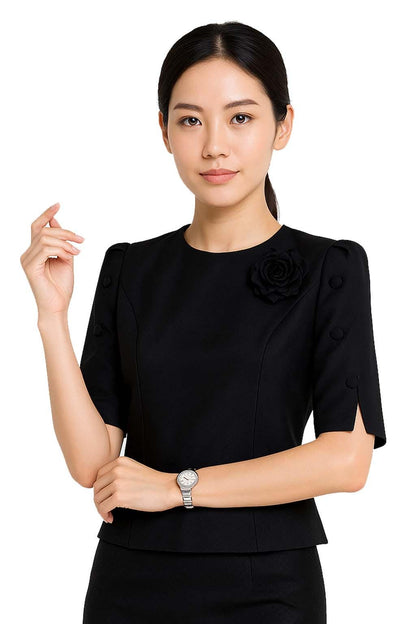 May include: A black short-sleeved blouse featuring a round neckline, a fabric rose embellishment on the left chest, and three decorative buttons on each sleeve. The sleeves have a small slit at the hem, and the blouse has a tailored, fitted silhouette.