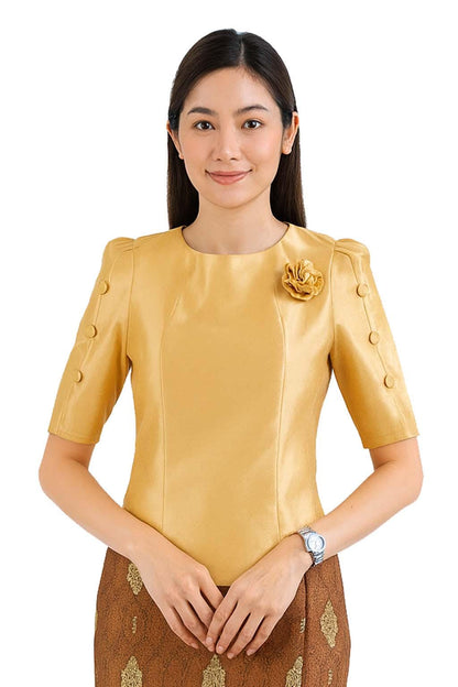 May include: A gold-colored blouse with a round neckline, short sleeves featuring three buttons on each side, and a matching fabric flower pinned to the left chest. The blouse is paired with a brown skirt featuring a gold-toned patterned design.