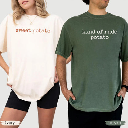 May include: Two t-shirts, one ivory and one moss green, are displayed. The ivory shirt has the words "sweet potato" in brown script. The moss green shirt has the words "kind of rude potato" in white. Both shirts are short-sleeved.