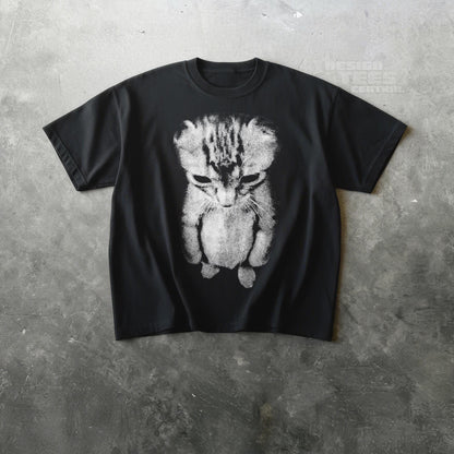 May include: Black t-shirt featuring a distressed, grayscale image of a sad-looking cat. The cat's fur is detailed with stripes and shading, and the design is centered on the shirt. The shirt has short sleeves and a crew neck.