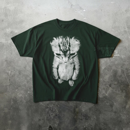 May include: Dark green t-shirt featuring a distressed, grayscale image of a sad-looking kitten. The graphic is centered on the shirt. The text "DESIGN TEES CENTRAL" is visible on the right side of the shirt.
