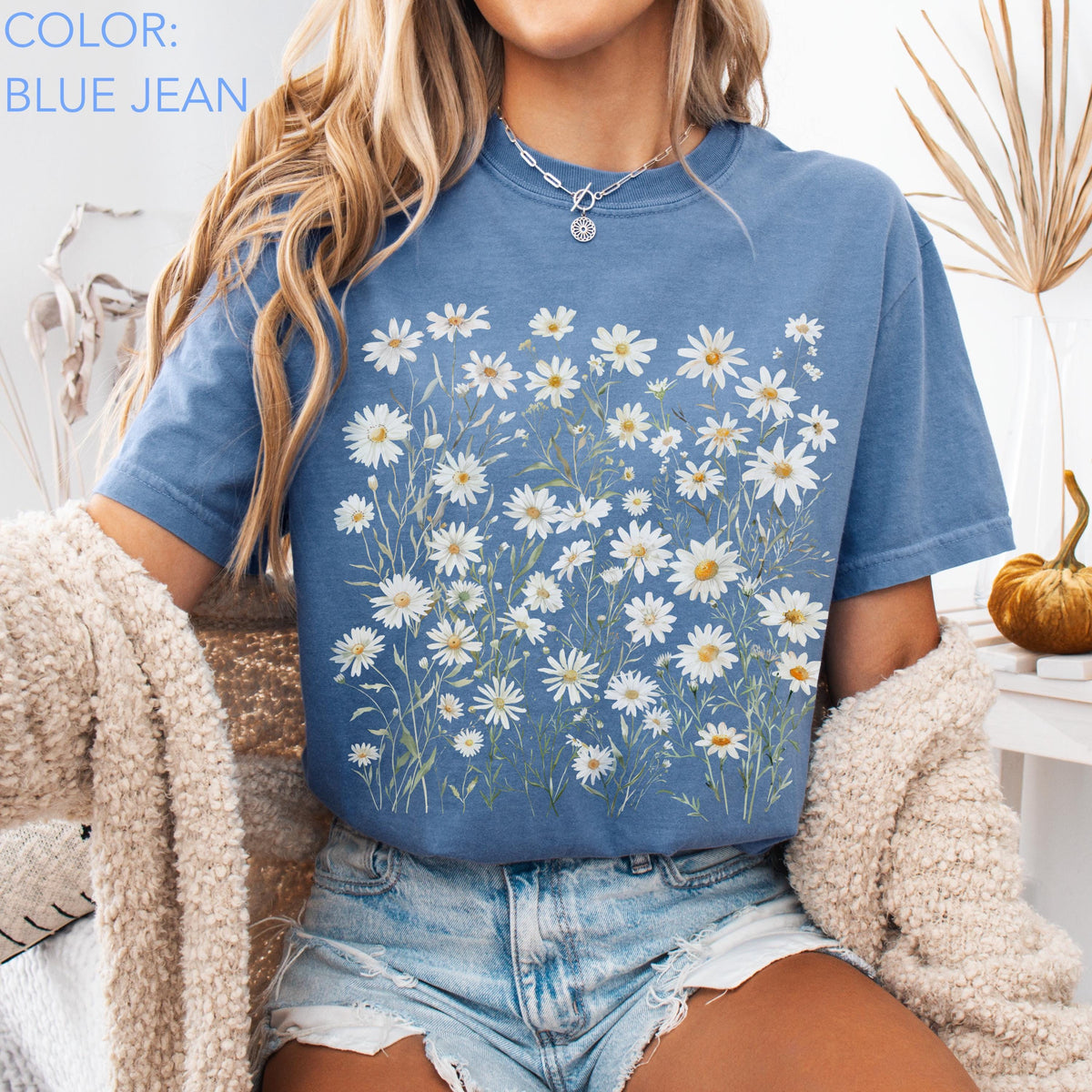 May include: Blue jean colored t-shirt with a daisy floral design. The shirt features a crew neck and short sleeves. The text "COLOR: BLUE JEAN" is visible in the upper left corner. The shirt is paired with denim shorts.
