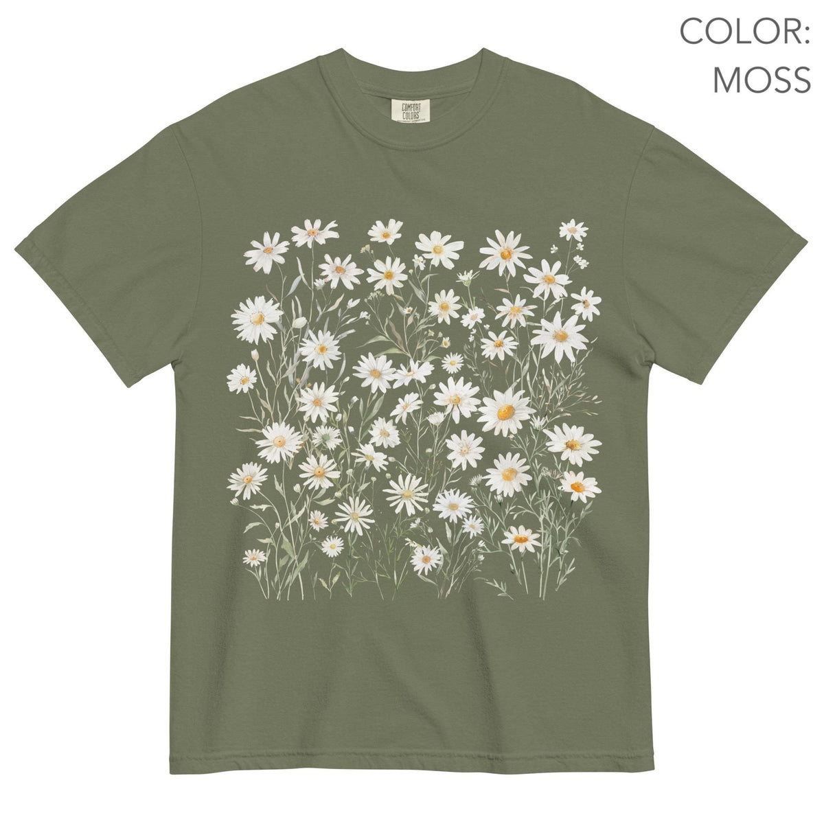 May include: Moss green t-shirt featuring a watercolor design of white daisies with yellow centers and green stems. The shirt has a classic crew neck and short sleeves. The text "COLOR: MOSS" is visible in the upper right corner.