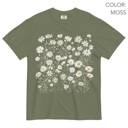 May include: Moss green t-shirt featuring a watercolor design of white daisies with yellow centers and green stems. The shirt has a classic crew neck and short sleeves. The text "COLOR: MOSS" is visible in the upper right corner.