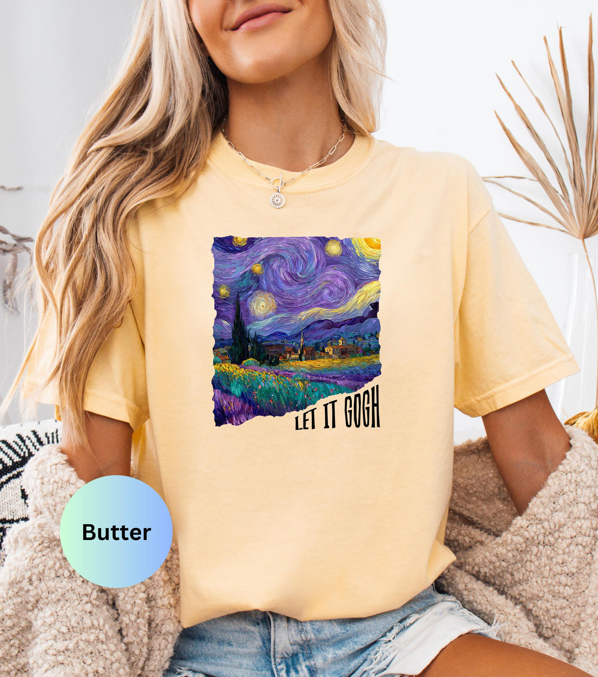 May include: Butter-colored t-shirt featuring a vibrant print of Van Gogh's "Starry Night" painting. The artwork showcases swirling blues, purples, and yellows, with the text "LET IT GOGH" in black. The shirt has short sleeves and a relaxed fit.