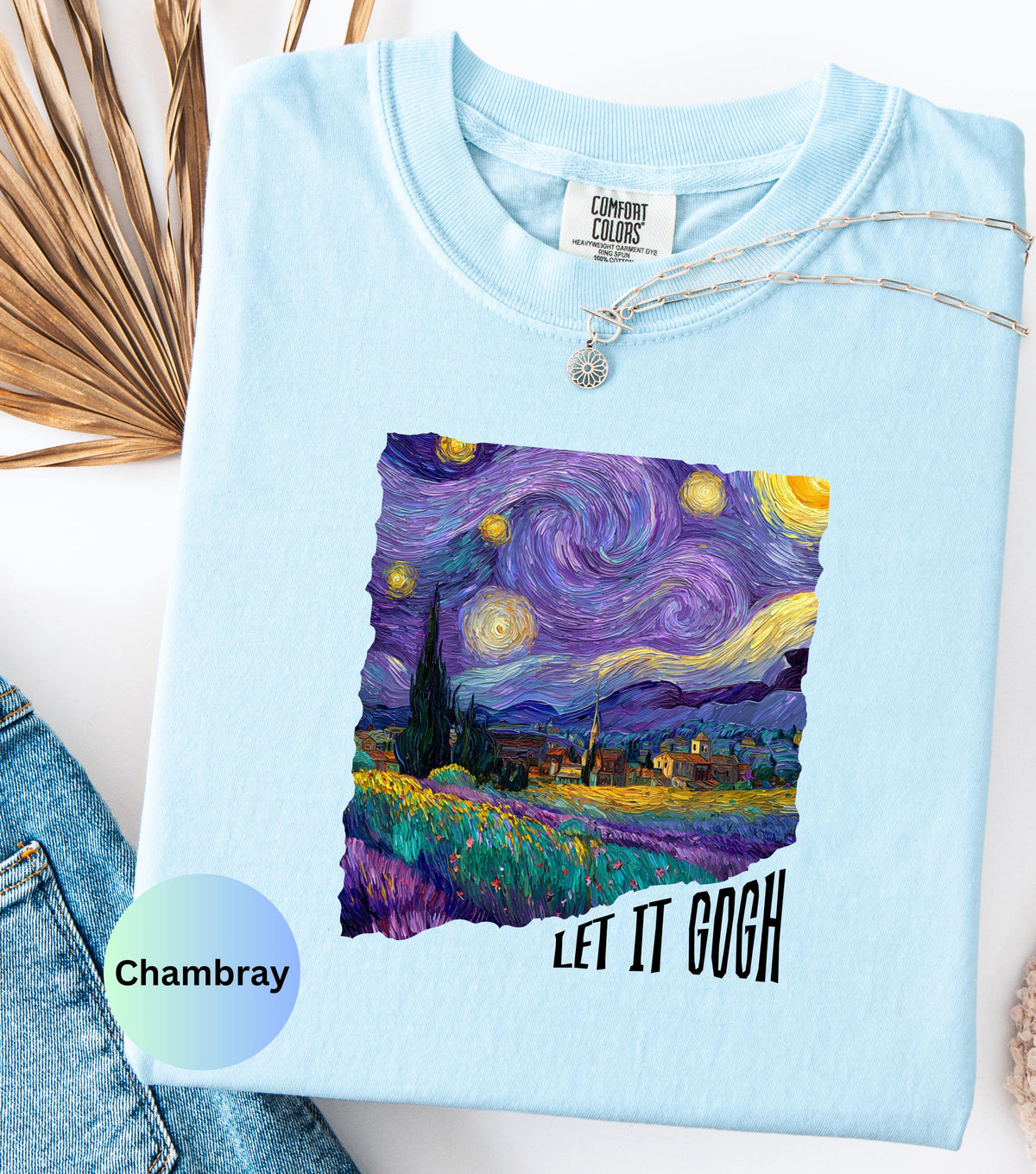 May include: Light blue Comfort Colors t-shirt featuring a vibrant print of Van Gogh's "Starry Night" painting. The design includes swirling blues, purples, and yellows, with the text "LET IT GOGH" in black. A silver necklace with a sun pendant is visible.