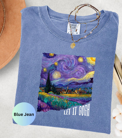 May include: Blue jean colored t-shirt featuring a vibrant print of Van Gogh's "Starry Night" painting. The shirt has the text "LET IT GOGH" in white. A necklace with a pendant rests on the shirt.