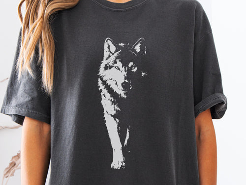 May include: Dark gray t-shirt featuring a white graphic of a wolf. The wolf is depicted in a detailed, artistic style, with a focus on its face and front legs. The shirt has short sleeves and a relaxed fit.
