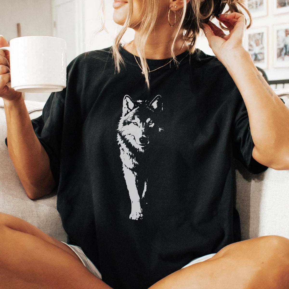 May include: Black t-shirt featuring a white graphic of a wolf. The wolf is depicted in a detailed, artistic style, with a focus on its face and front legs. The shirt is a casual style, suitable for everyday wear.