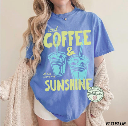 May include: A blue t-shirt with the words "iced COFFEE & SUNSHINE" in yellow and two iced coffee cup illustrations. The shirt also has the text "all day every day". The shirt is a Flo Blue color.