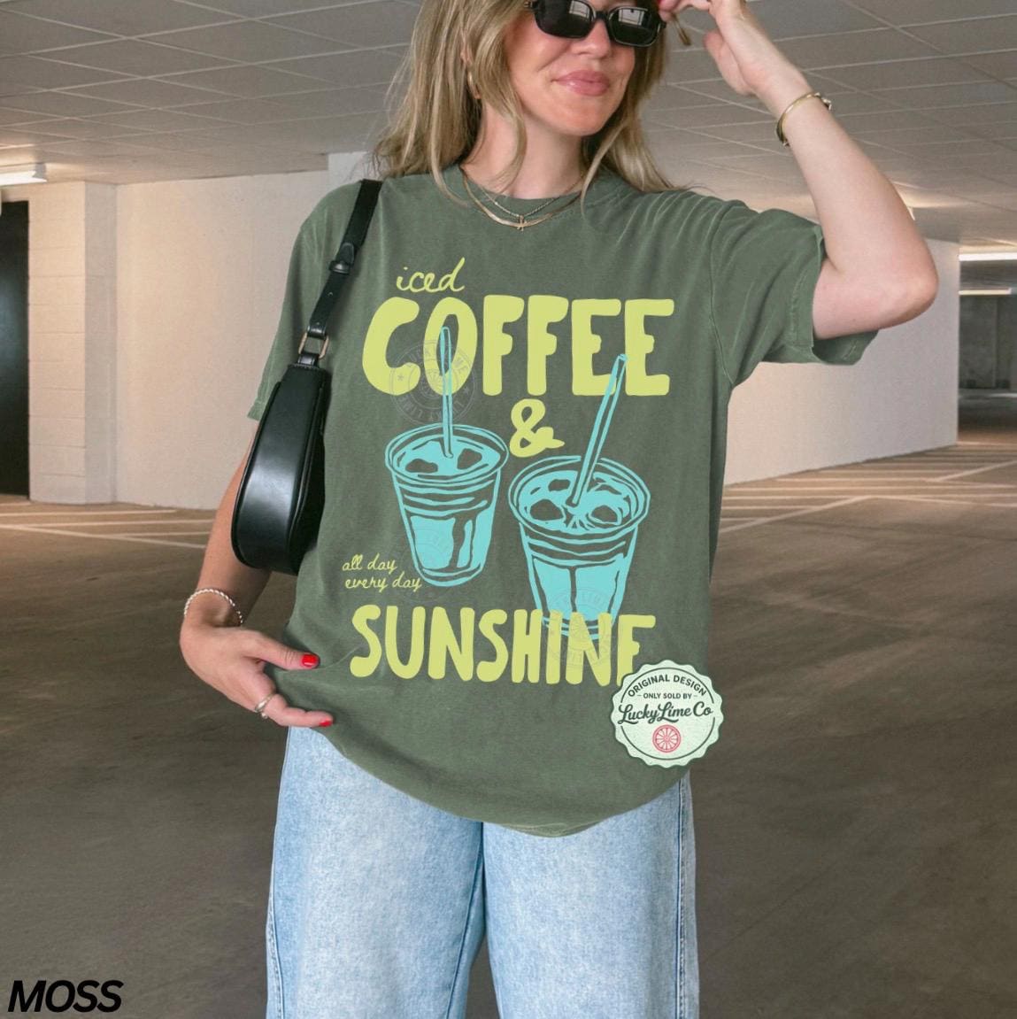 May include: Olive green t-shirt with the words "iced COFFEE & SUNSHINE" in yellow and teal. The graphic features two iced coffee cups. The shirt also has the text "all day every day" and a logo that says "Original Design Lucky Lime Co."