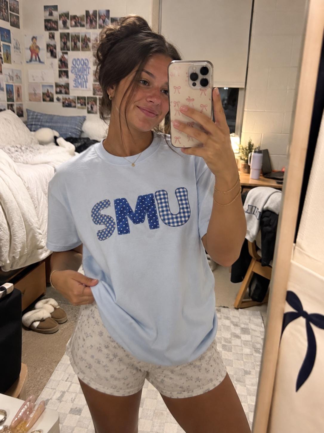 May include: A light blue short-sleeve t-shirt featuring the letters SMU in a blue and white patterned fabric appliqué. The letters display a mix of polka dot and gingham check designs, centered on the chest of the crew neck cotton shirt.