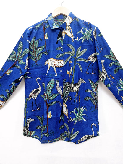 May include: A long-sleeved blue button-down shirt with a vibrant jungle print. The design features leopards, zebras, birds, and palm trees. The shirt is made of a lightweight fabric and is displayed on a wooden hanger.