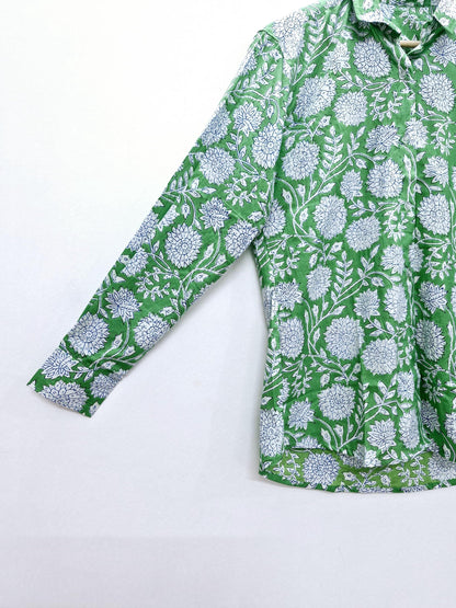May include: Green long-sleeve shirt with a white floral pattern. The shirt features a button-down design and a classic collar. The floral print is detailed and covers the entire shirt, creating a vibrant and stylish look.