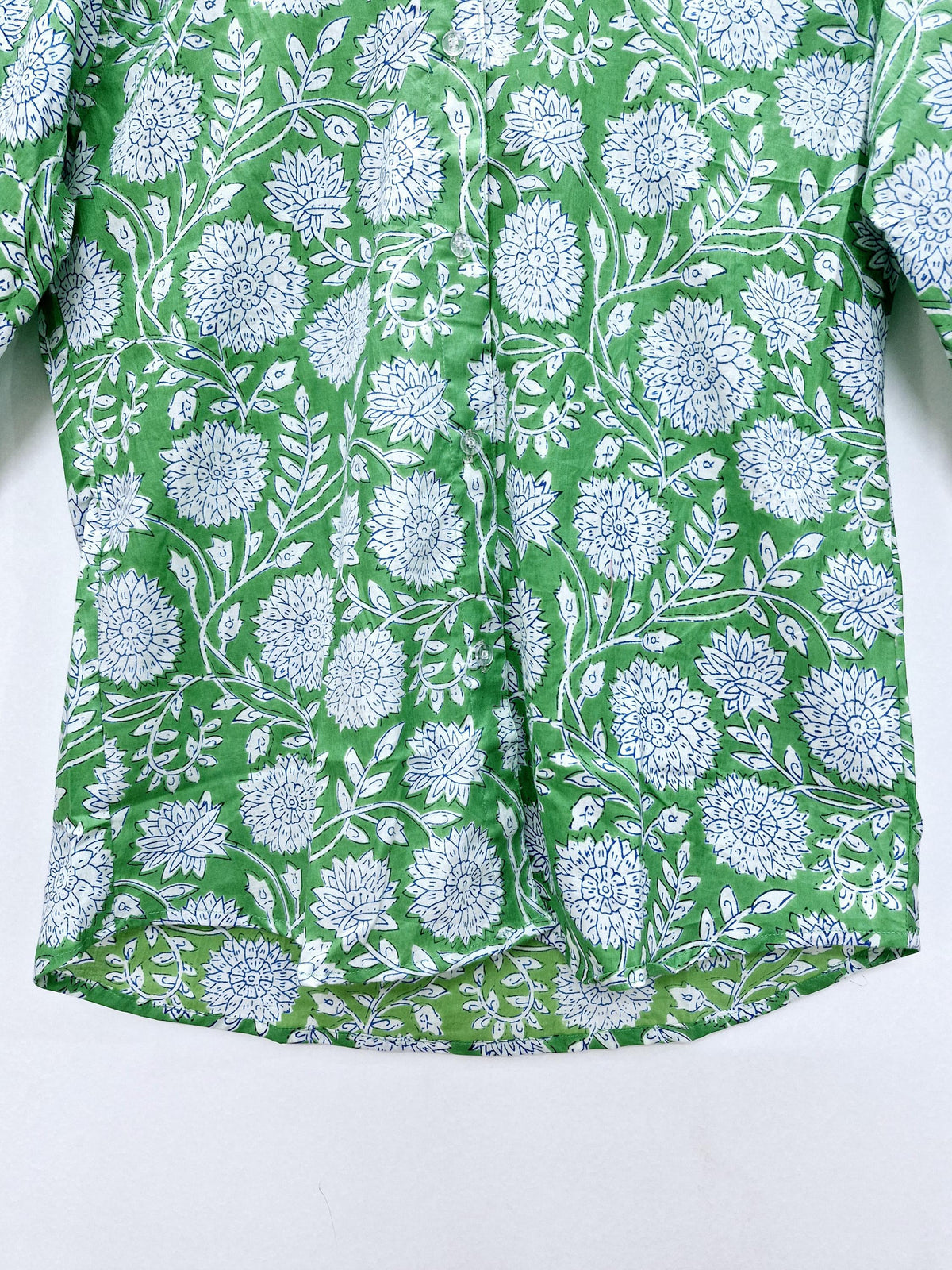 May include: Green button-down shirt with a white and blue floral pattern. The shirt features a repeating design of large flowers and leaves. The fabric has a slightly textured appearance.