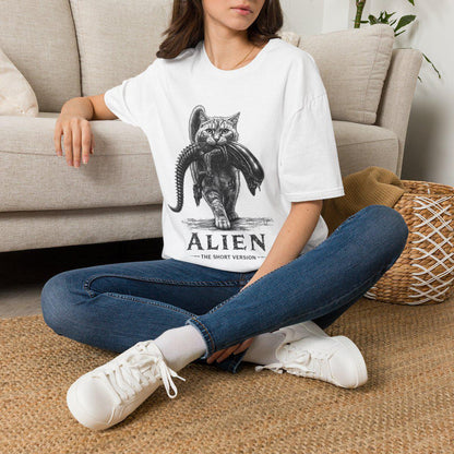 May include: A white short-sleeved t-shirt featuring a black and white graphic illustration of a cat carrying a xenomorph creature in its mouth. Below the illustration, the text reads ALIEN THE SHORT VERSION in a bold, distressed black font.