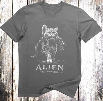 May include: A charcoal gray short-sleeved t-shirt featuring a white graphic of a cat carrying a xenomorph creature in its mouth. Below the illustration, the text reads ALIEN THE SHORT VERSION in a distressed white font centered on the chest.