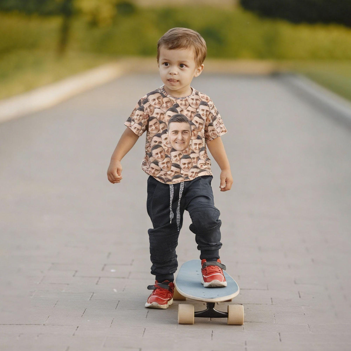 May include: A short-sleeved t-shirt featuring an all-over repeating pattern of a single face, paired with dark charcoal joggers that have a white drawstring and red athletic sneakers, worn while standing on a light blue skateboard.