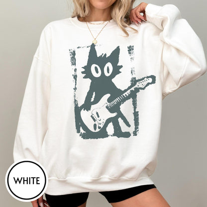 May include: A white crewneck sweatshirt featuring a dark gray graphic print of a stylized cat playing an electric guitar. The cat is positioned within a rectangular, distressed-edge frame. The sweatshirt has long sleeves and a ribbed neckline.