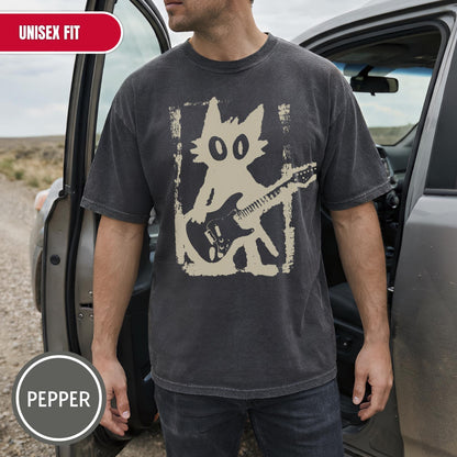 May include: A charcoal gray short-sleeve t-shirt featuring a cream-colored graphic of a cat playing an electric guitar. The cat is depicted in a stylized, distressed rectangular frame. The shirt has a crew neckline and a relaxed, casual fit.