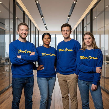 May include: Four people wearing blue sweatshirts with the text "Titan Crew" in yellow script. The people are standing in a modern office setting with glass walls and a wooden floor. The sweatshirts are long-sleeved.
