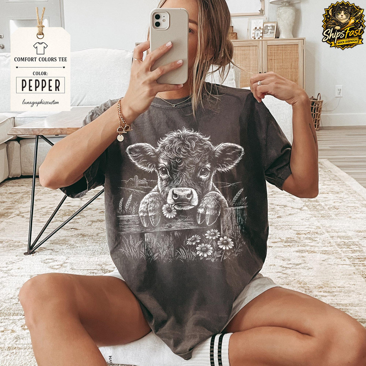 May include: Pepper-colored Comfort Colors tee featuring a graphic of a calf peering over a wooden fence with daisies. The tee has the text "Pepper" and "lunagraphiccustom" on a tag.